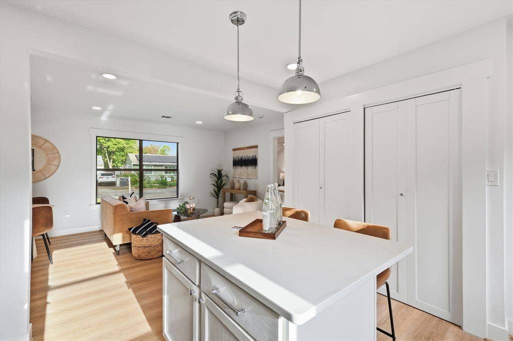 11624 Rupley Lane, Dallas, TX 75218 Kitchen island with a solid surface countertop, dual metal pendant lighting, wood-finish flooring, and floor-to-ceiling cabinetry