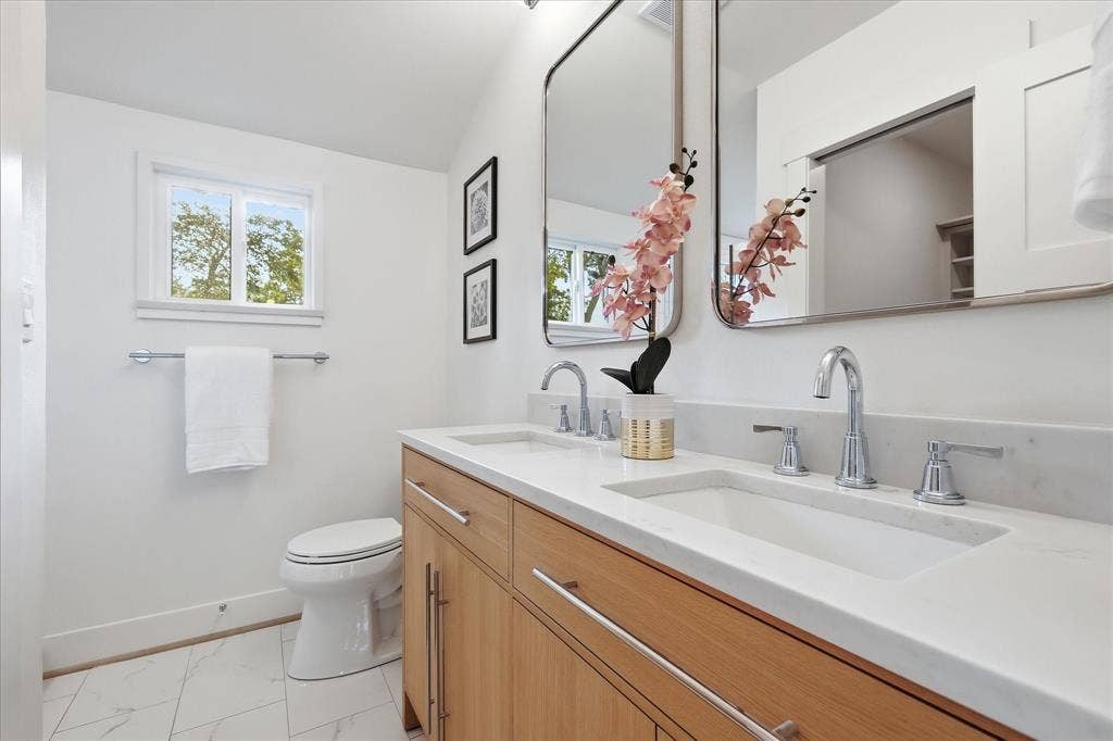 11624 Rupley Lane, Dallas, TX 75218 Double vanity featuring light wood cabinetry, white stone countertops, dual under-mount sinks, chrome widespread faucets, and twin rectangular mirrors