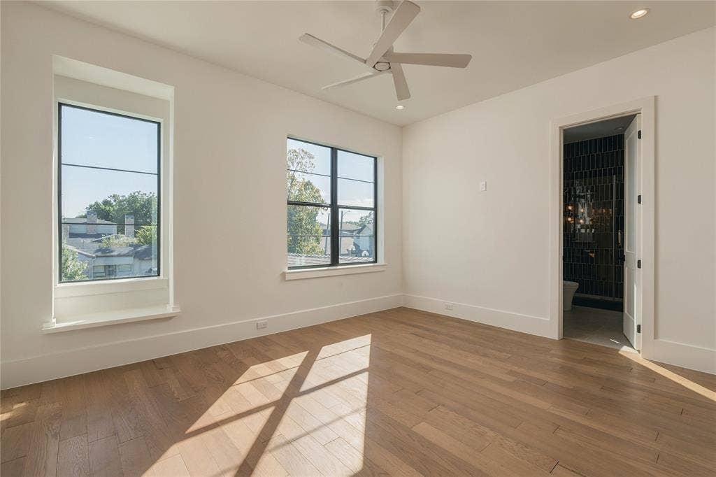 Interior room featuring wood-finish flooring, multi-pane windows with black frames, and a modern ceiling fan