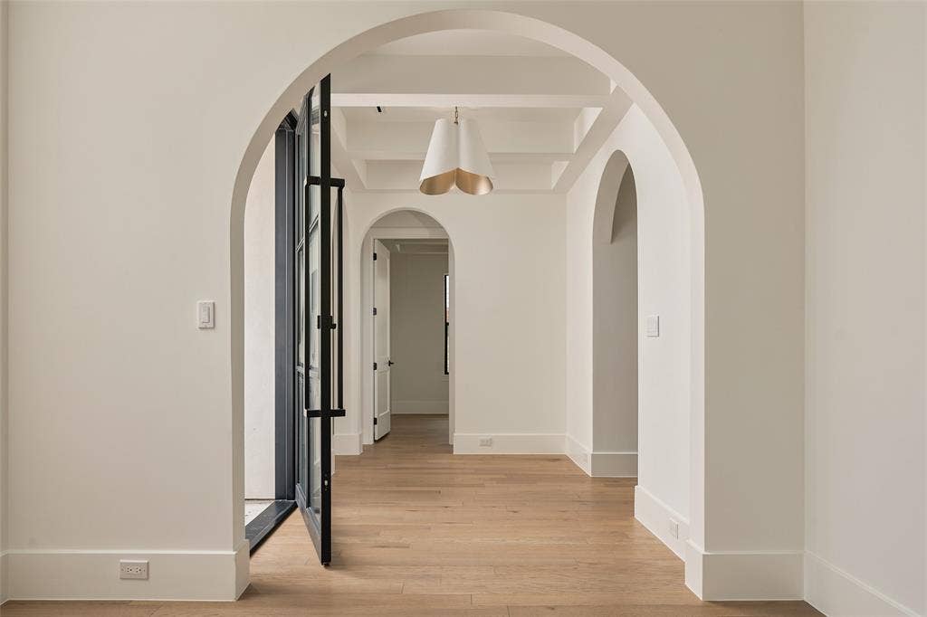 Interior featuring arched doorways, wood-finish flooring, coffered ceilings, and a decorative pendant light fixture