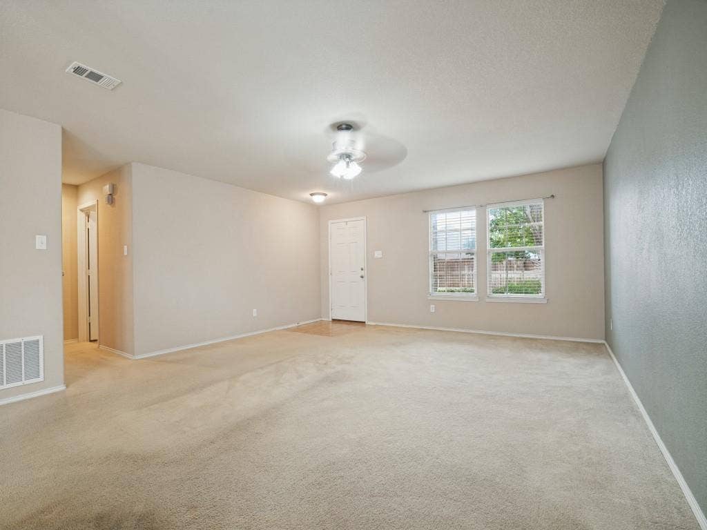Spacious main living area with ceiling fan and windows overlooking the front yard.