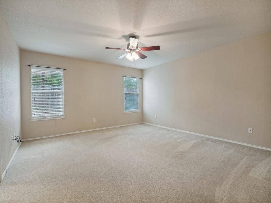 Spacious primary bedroom with ceiling fan and room for a complete bedroom suite.