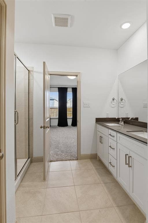 3125 Lucia Way, Princeton, TX 75407 Bathroom featuring a dual-sink vanity with white cabinetry, dark solid-surface countertops, large wall-mounted mirror, and a glass-enclosed shower with tile surround