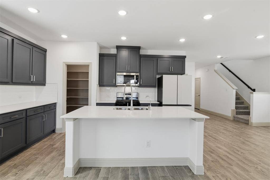 3125 Lucia Way, Princeton, TX 75407 Kitchen featuring charcoal cabinetry, central island with quartz countertop, walk-in pantry, wood-finish flooring, and recessed lighting