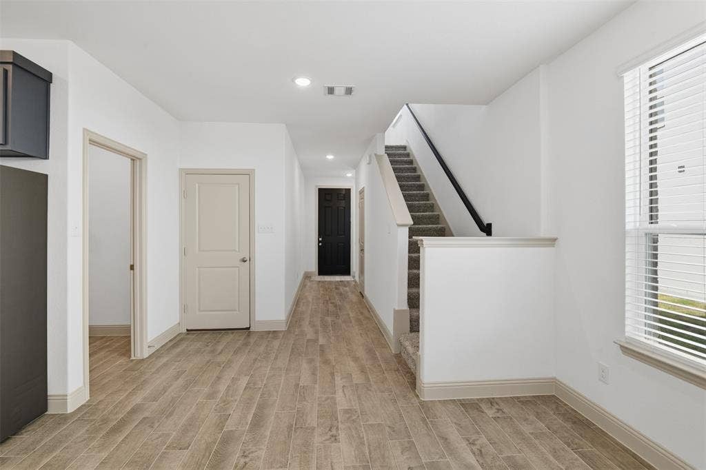 3125 Lucia Way, Princeton, TX 75407 Interior featuring wood-finish tile flooring, recessed lighting, staircase with carpeted treads and a matte black handrail, and windows with horizontal blinds