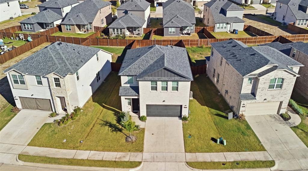 3125 Lucia Way, Princeton, TX 75407 Two-story residence featuring a light brick facade, metal roofing accents, asphalt shingle roofing, and an attached two-car garage