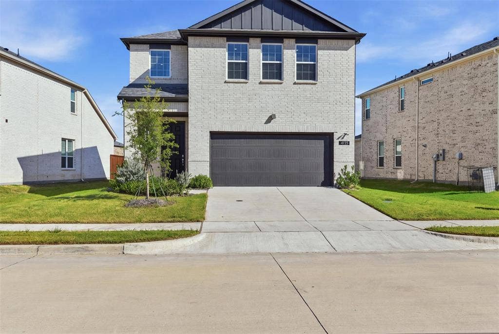 3125 Lucia Way, Princeton, TX 75407 Two-story exterior featuring a light-toned brick facade, dark metal roofing accents, vertical siding gables, and a double-car garage