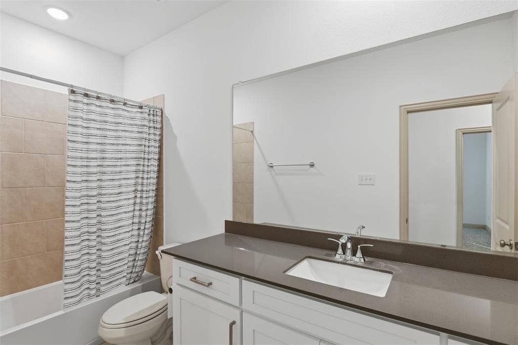 3125 Lucia Way, Princeton, TX 75407 Bathroom featuring white cabinetry, quartz countertop with an integrated rectangular sink, large wall-mounted mirror, and tile-surround shower