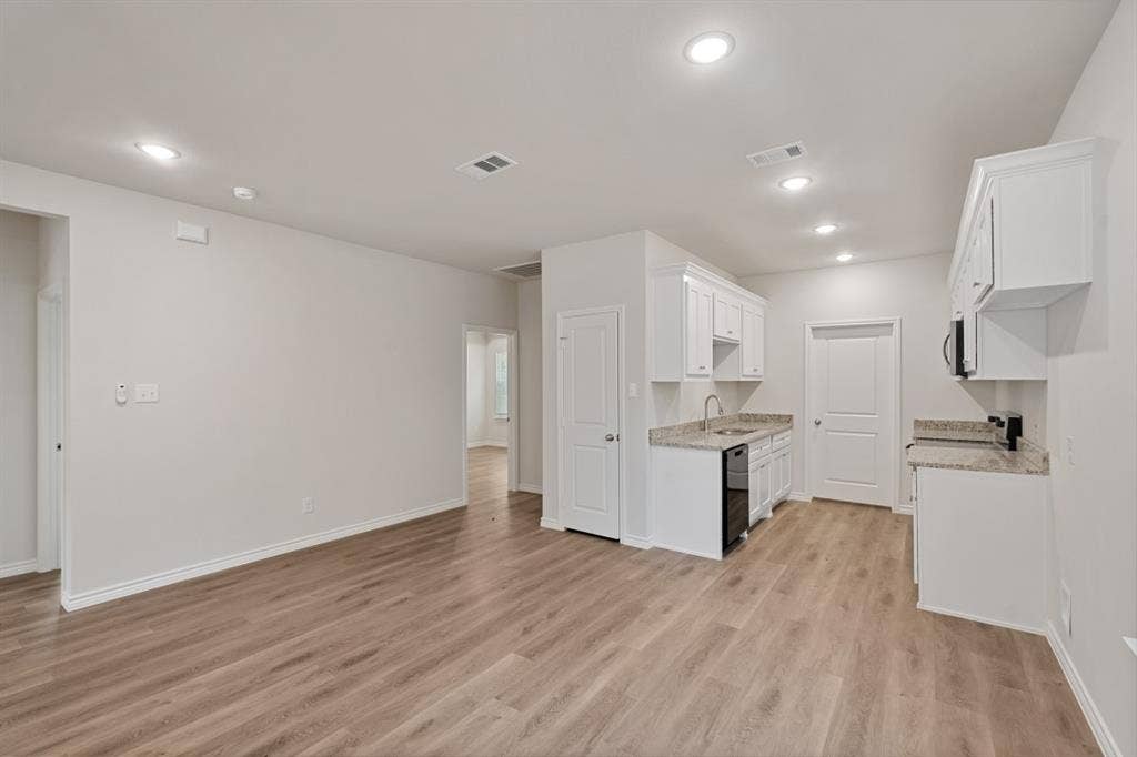 6144 Shawnee Drive, Mabank, TX 75156 Open interior space featuring wood-finish flooring, recessed lighting, white cabinetry, neutral stone-finish countertops, and a stainless steel sink