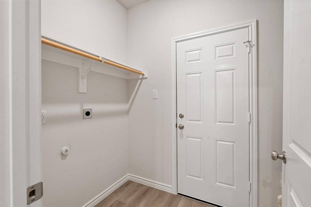 6144 Shawnee Drive, Mabank, TX 75156 Utility room featuring wood-finish flooring, a six-panel door, and a built-in wall-mounted garment rod
