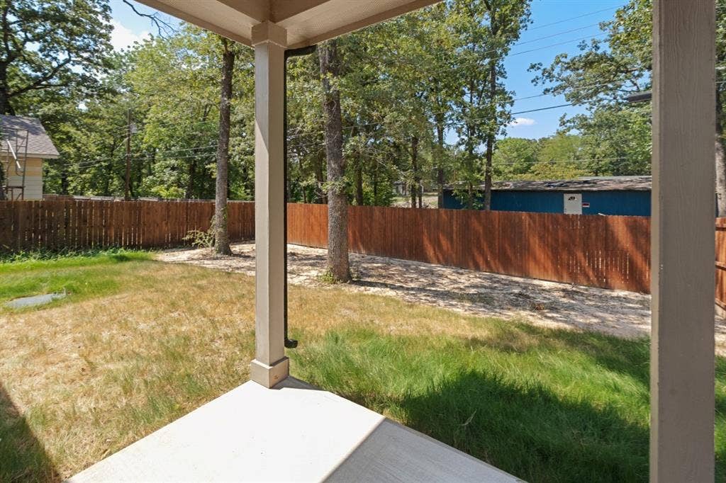 6144 Shawnee Drive, Mabank, TX 75156 Covered porch featuring concrete flooring and wooden support columns, overlooking a fenced backyard with mature trees