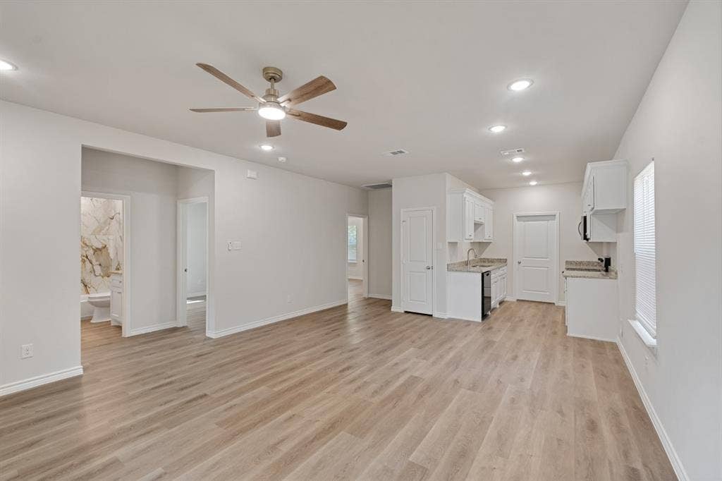 6144 Shawnee Drive, Mabank, TX 75156 Open-concept interior featuring wood-finish flooring, recessed lighting, a ceiling fan with integrated light, and a kitchen area with white cabinetry and stone-surfaced countertops