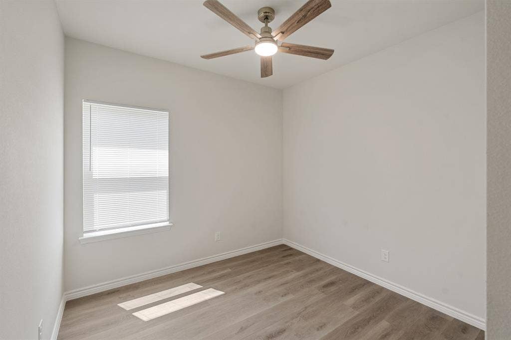6144 Shawnee Drive, Mabank, TX 75156 Neutral-toned interior space featuring wood-finish flooring, a ceiling fan with integrated lighting, and a single-hung window with installed blinds