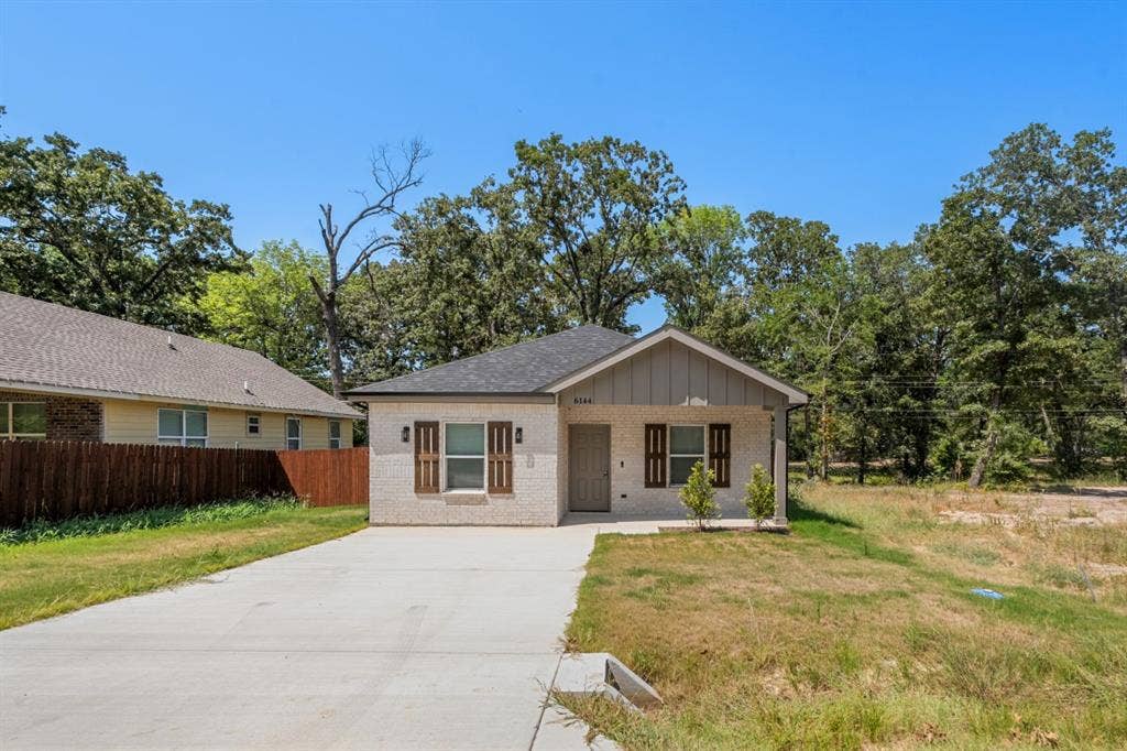 6144 Shawnee Drive, Mabank, TX 75156 Single-story residence featuring a light-toned brick facade, gabled roofline, concrete driveway, and decorative window shutters