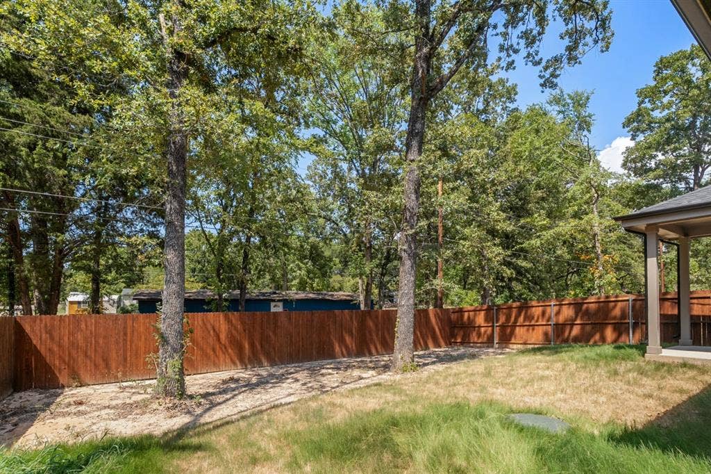 6144 Shawnee Drive, Mabank, TX 75156 Backyard featuring a wood-panel fence, mature trees, and a covered patio area