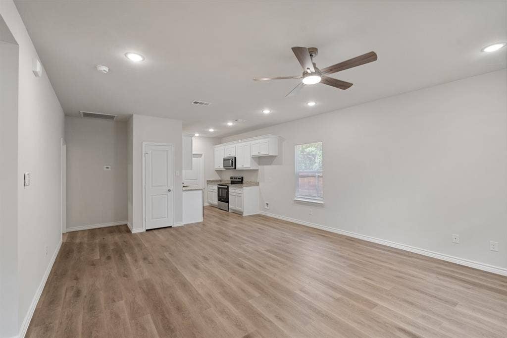 6144 Shawnee Drive, Mabank, TX 75156 Open-concept interior featuring wood-finish flooring, recessed lighting, a ceiling fan, and white cabinetry paired with stainless steel appliances