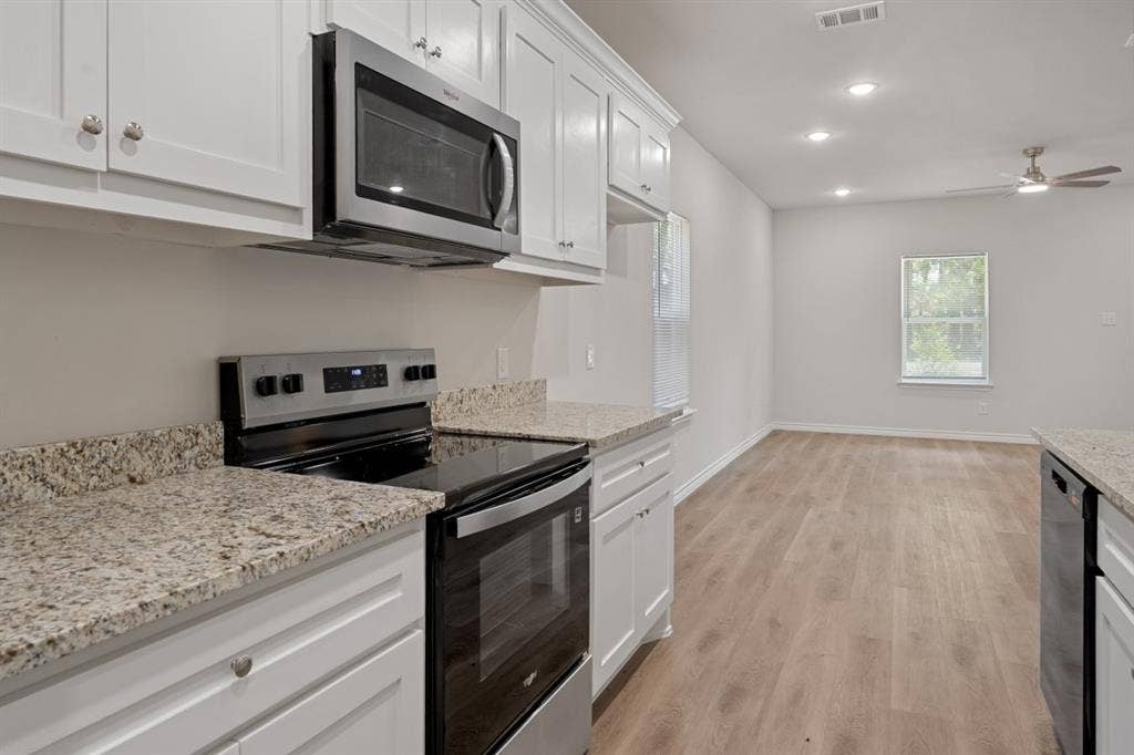 6144 Shawnee Drive, Mabank, TX 75156 Kitchen featuring white shaker-style cabinetry, stone-finish countertops, stainless steel appliances, and wood-finish flooring