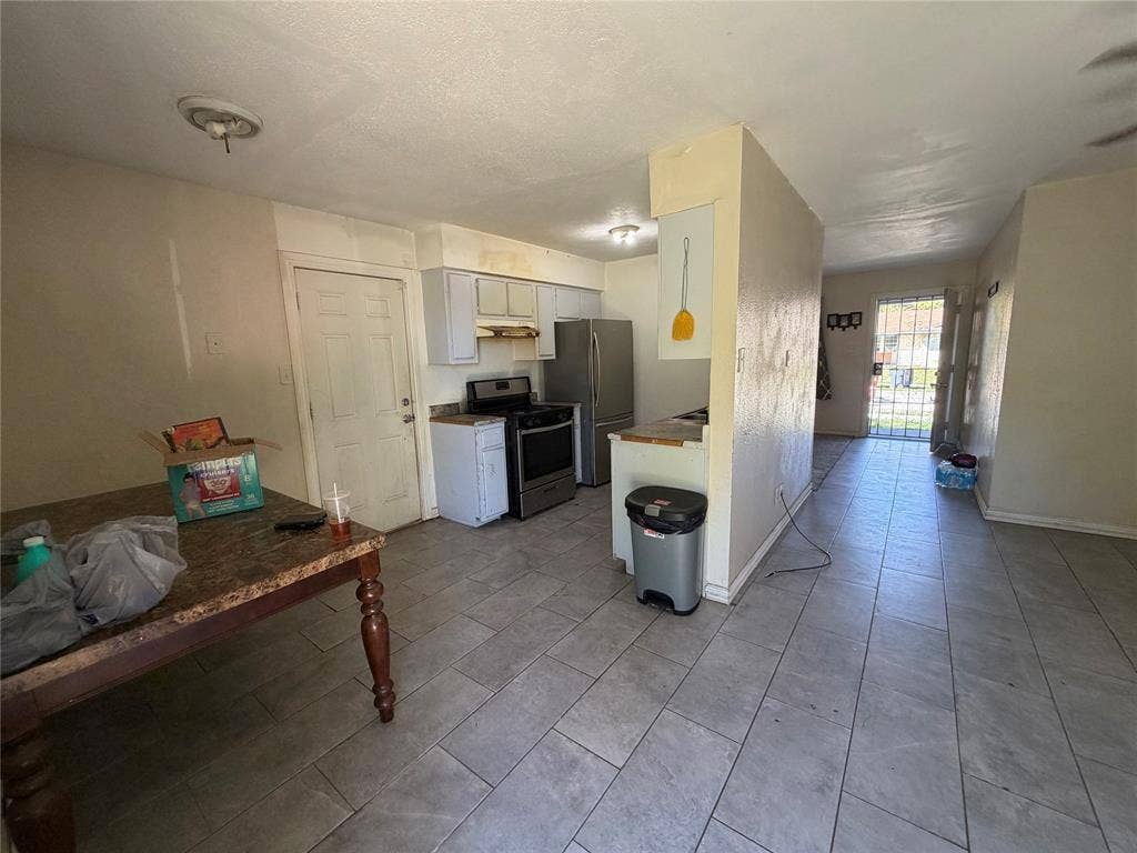 Kitchen featuring tile flooring, white cabinetry, and stainless steel appliances