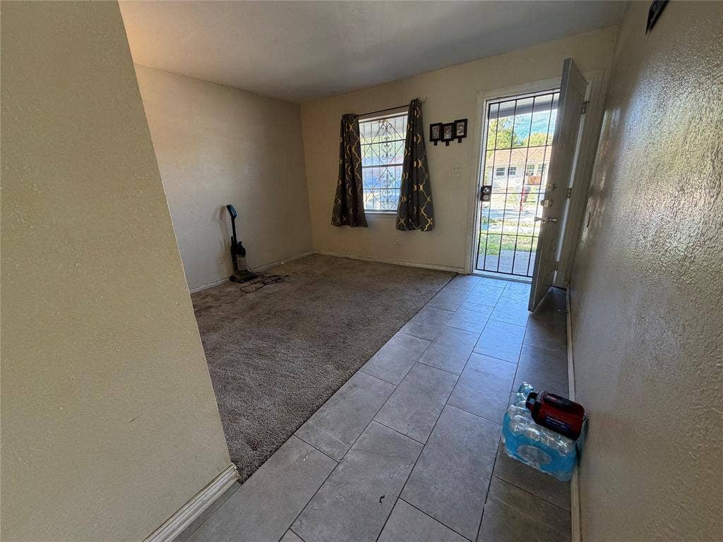 Interior space featuring large-format tile flooring, wall-to-wall carpeting, and a metal security door with integrated glass panel