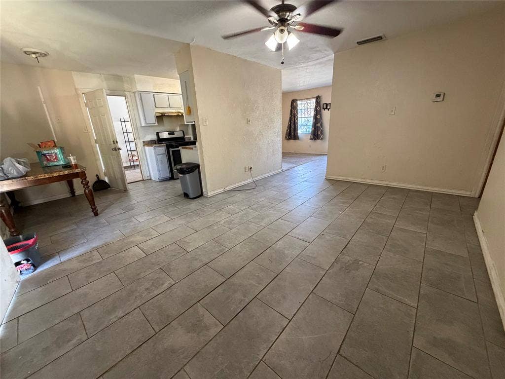 Large format ceramic tile flooring and a ceiling-mounted light fixture with a multi-blade fan