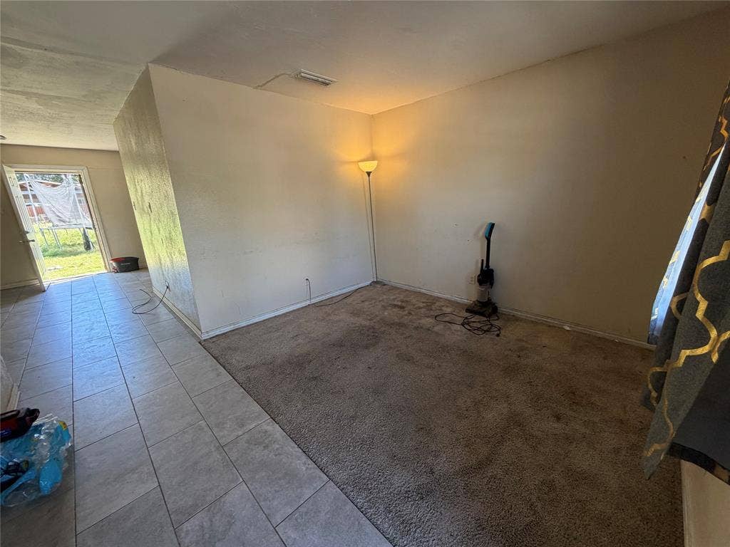 Neutral-toned carpeted flooring with tile flooring accents and a glass-paneled entry door