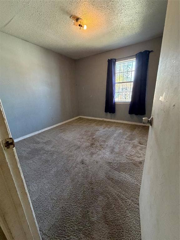 Neutral-toned interior space featuring wall-to-wall carpeting and a single-pane window with decorative security grating