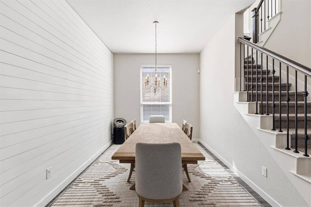Horizontal shiplap wall treatment, iron spindle staircase railing, and multi-arm chandelier lighting