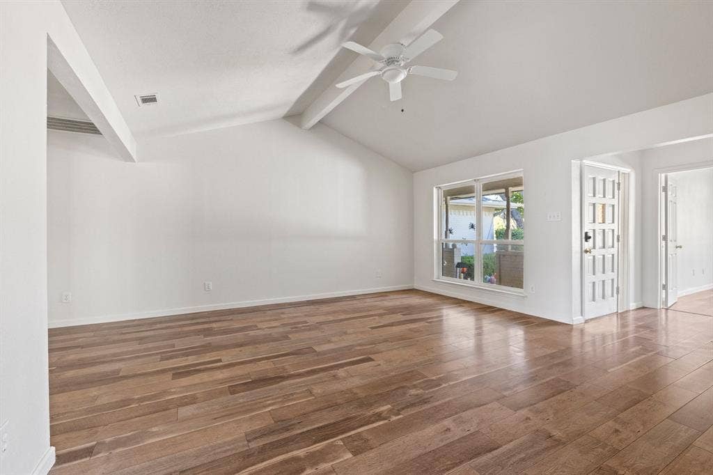Vaulted ceiling with an integrated white ceiling fan, wood-finish flooring, and a multi-lite exterior entry door