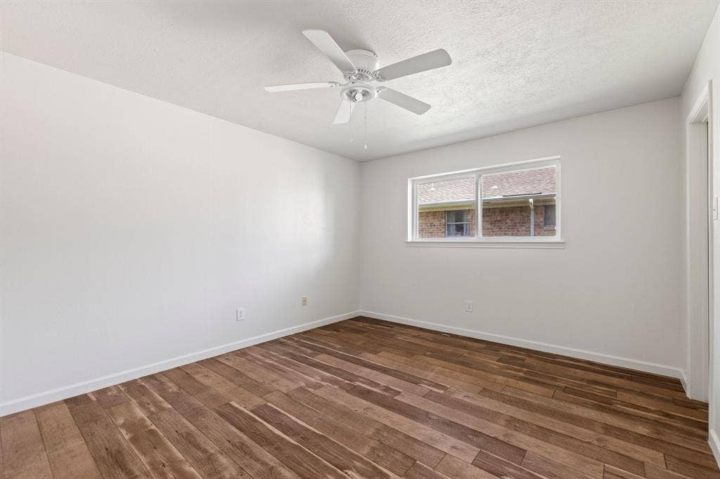 Interior space featuring wood-finish flooring, white walls, and a ceiling fan with integrated lighting