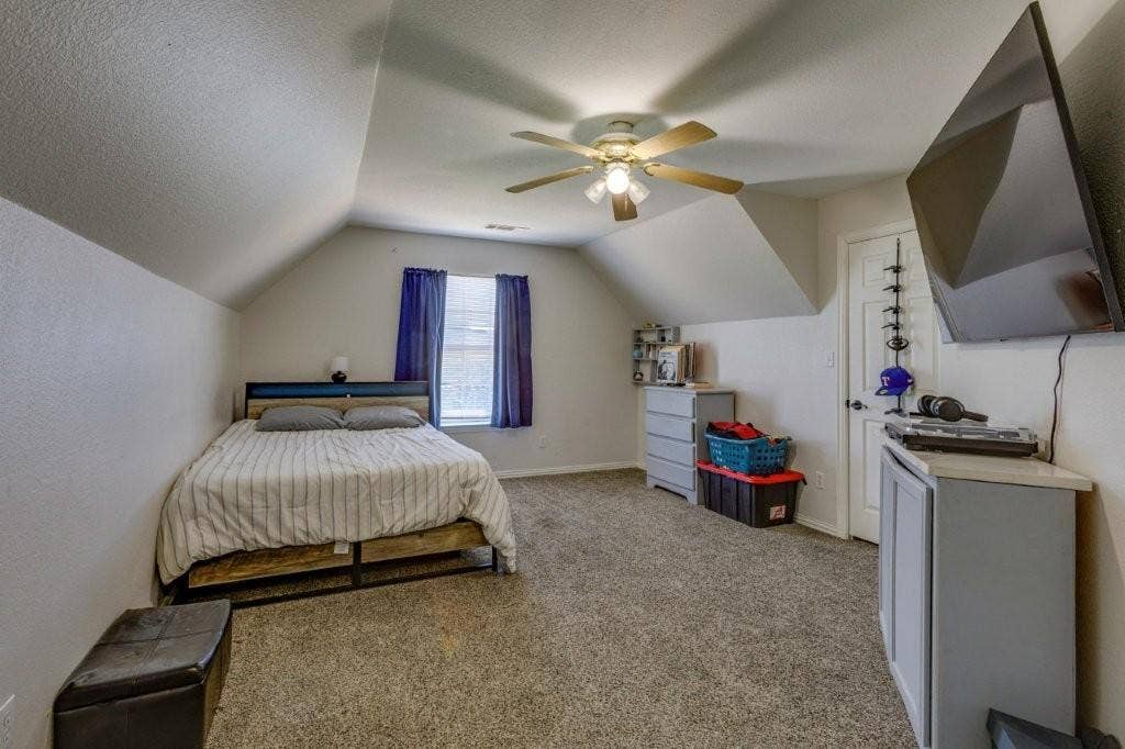 Room featuring sloped ceilings, carpeted flooring, and a ceiling fan with integrated lighting
