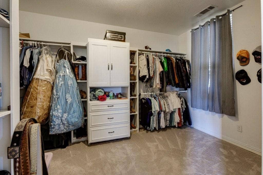 Custom walk-in closet featuring white built-in cabinetry, tiered shelving units, integrated dresser drawers, and dual-level hanging rods