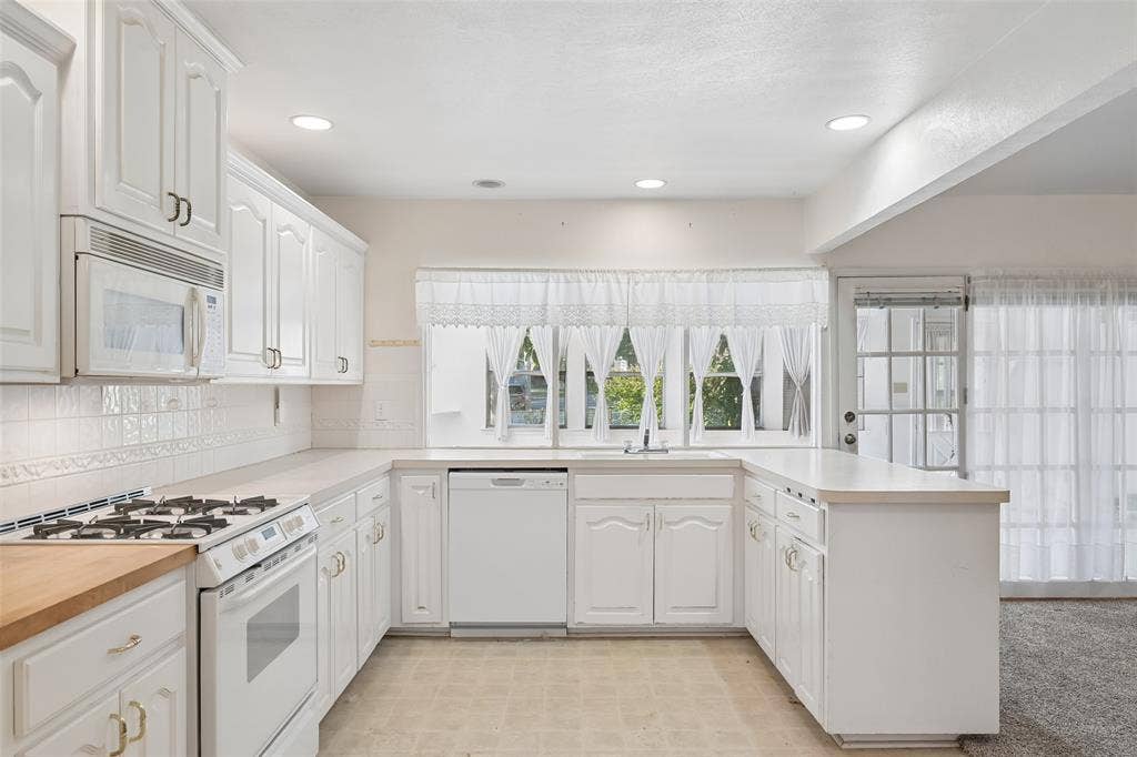 3309 S Edelweiss Drive, Grand Prairie, TX 75052 U-shaped layout with a dishwasher and garden views over the sink.