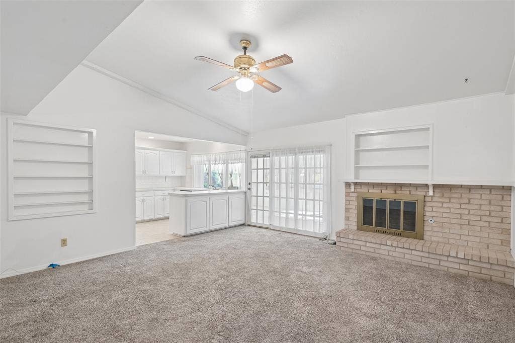 3309 S Edelweiss Drive, Grand Prairie, TX 75052 Vaulted ceiling, built-in shelves and a brick wood-burning fireplace anchor the living room.