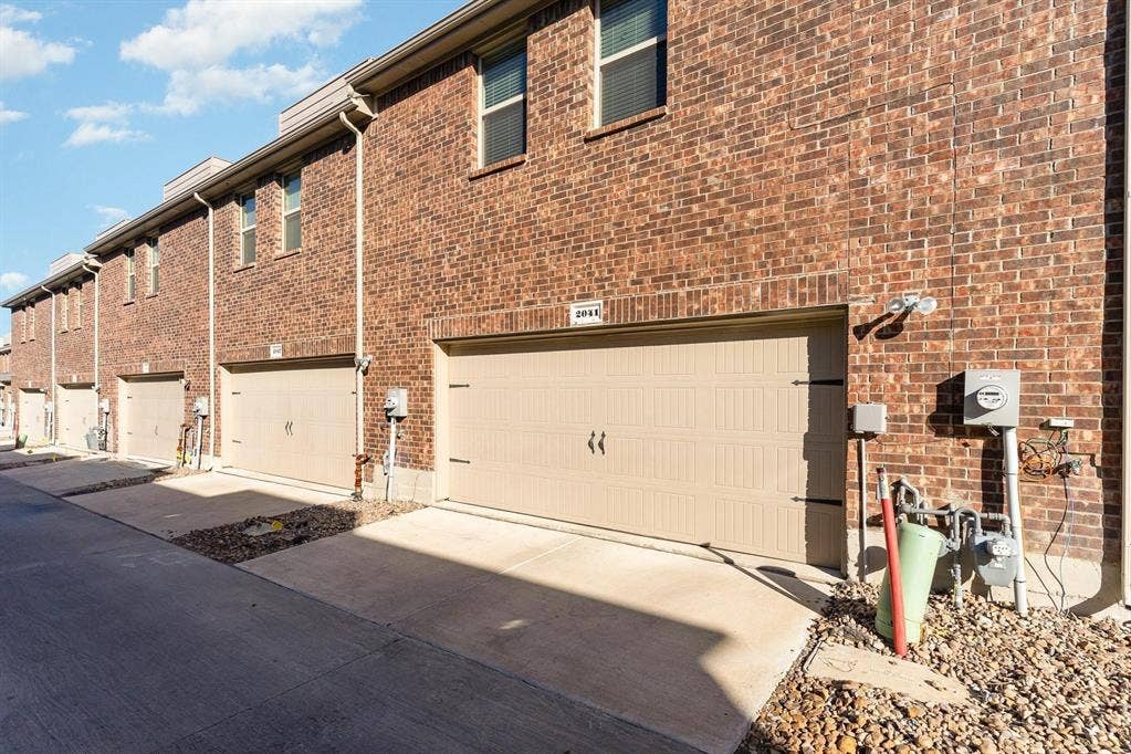 Multi-story brick exterior featuring attached dual-car garages, concrete driveways, and upper-level windows