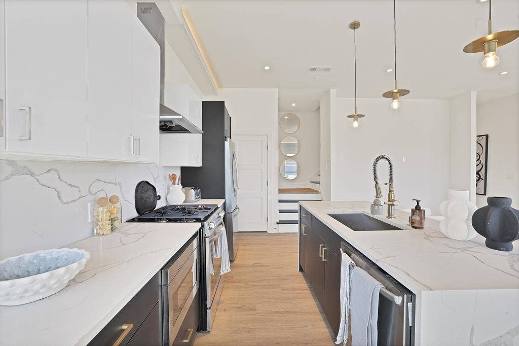 1731 N Fitzhugh Avenue, Dallas, TX 75204 Kitchen featuring decorative light fixtures, white cabinetry, sink, light stone counters, and stainless steel appliances