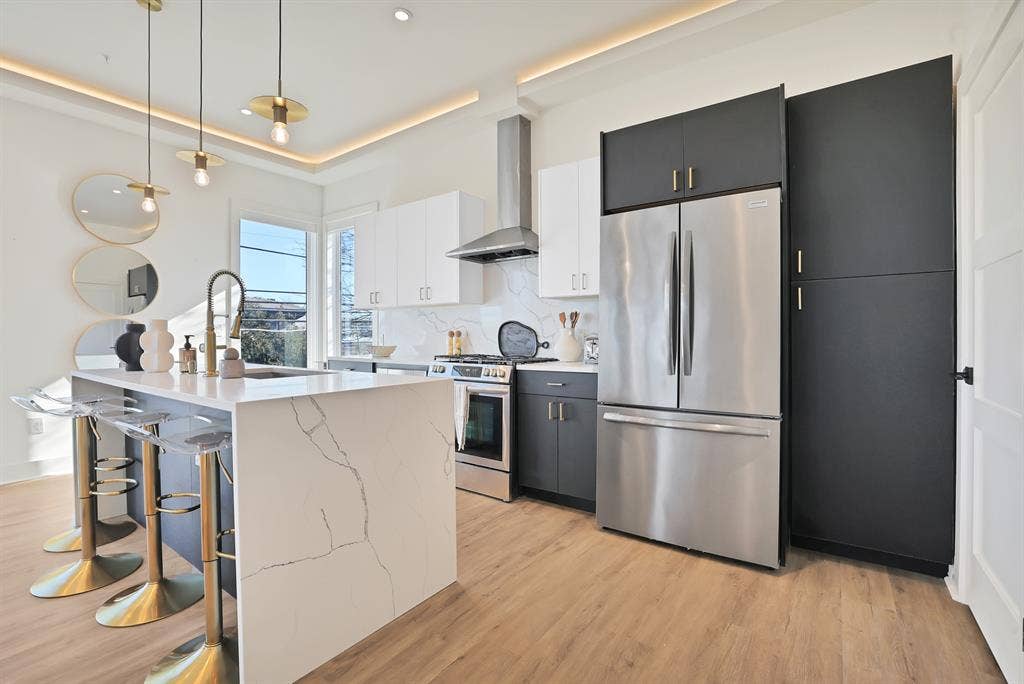 1731 N Fitzhugh Avenue, Dallas, TX 75204 Kitchen with appliances with stainless steel finishes, decorative light fixtures, tasteful backsplash, white cabinetry, and wall chimney exhaust hood