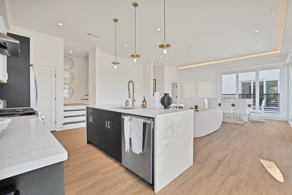 1731 N Fitzhugh Avenue, Dallas, TX 75204 Kitchen with a large island, sink, stainless steel appliances, light stone countertops, and decorative light fixtures