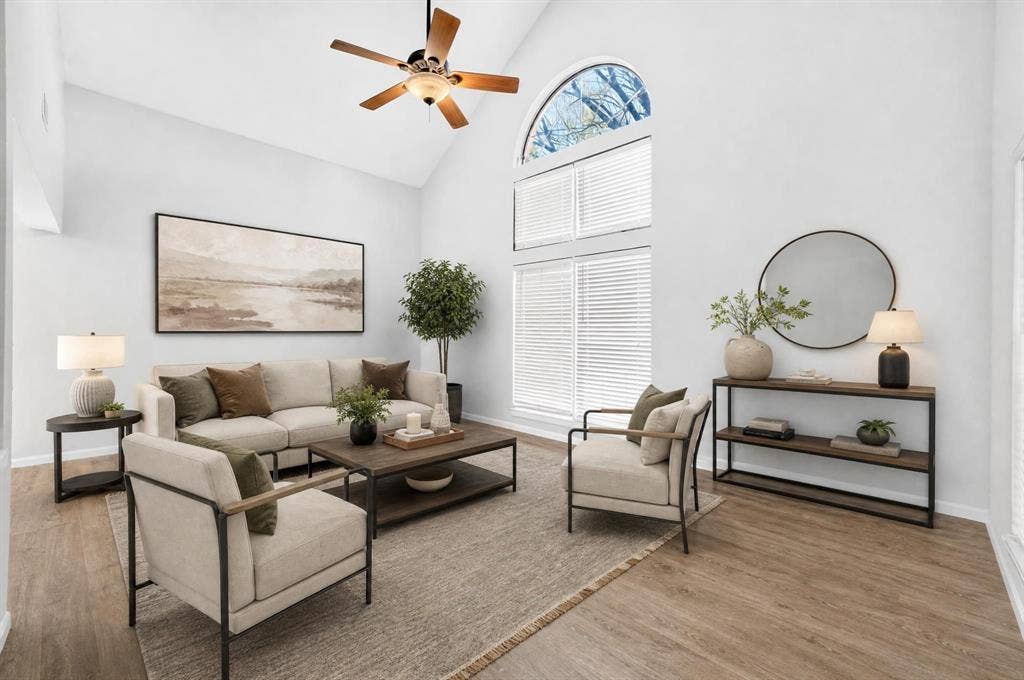 Vaulted ceilings featuring an arched window, wood-finish flooring, and a ceiling fan with integrated lighting
