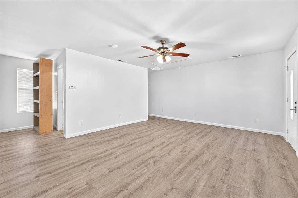 2nd master bedroom Interior space featuring neutral wall paint, wood-finish flooring, a ceiling fan with integrated lighting, and built-in shelving