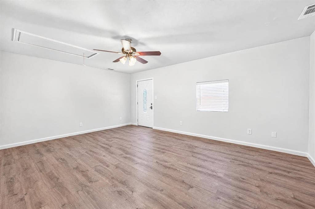 Interior space featuring wood-finish flooring, a ceiling fan with integrated lighting, and a single-panel exterior door with a decorative glass insert