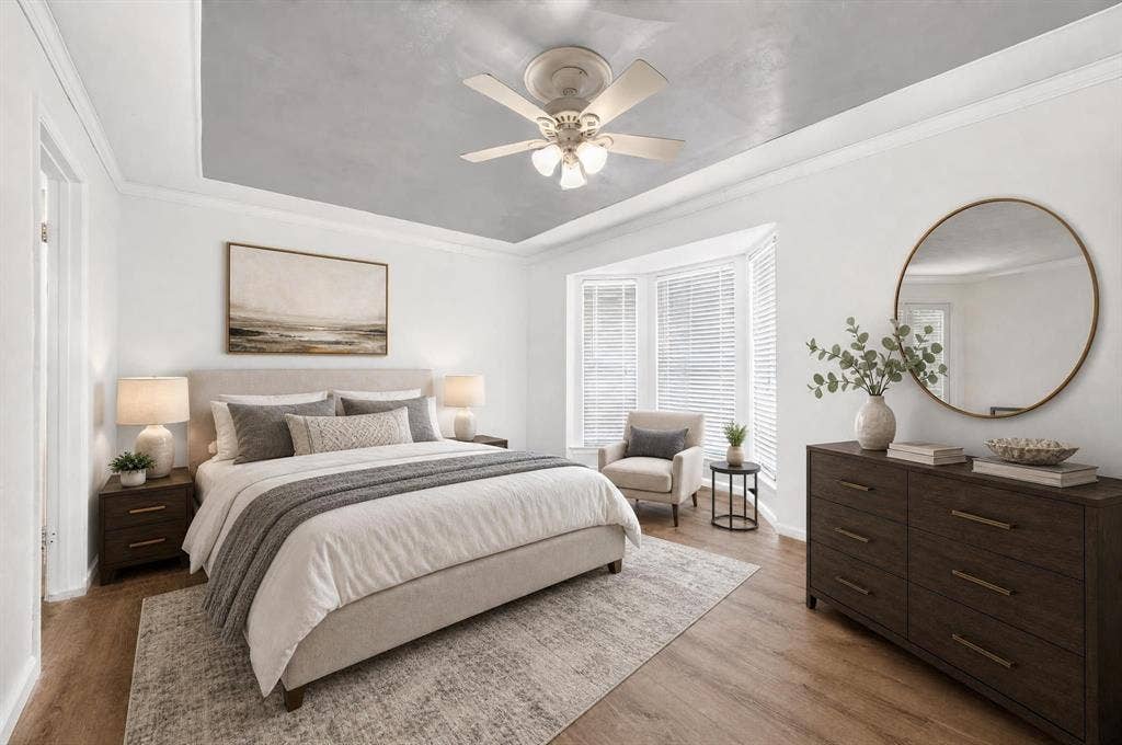 Tray ceiling with grey finish, wood-finish flooring, and bay window featuring integrated blinds