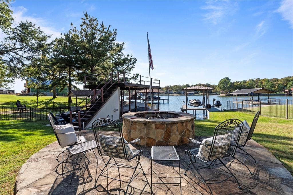 230 Bushwhacker Drive, Mabank, TX 75156 Flagstone patio featuring a circular stone fire pit, metal-railed waterfront staircase, and private boat slip