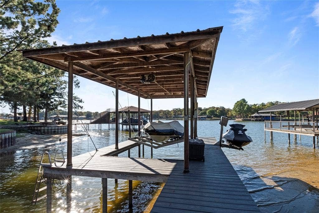 230 Bushwhacker Drive, Mabank, TX 75156 Covered boat dock featuring wood decking, a metal roof structure, and a ladder for water access
