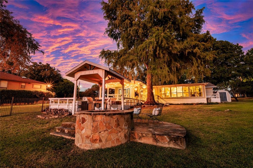 230 Bushwhacker Drive, Mabank, TX 75156 Expansive grounds featuring a stone-clad fire pit, a covered outdoor pavilion with a raised wooden deck, and mature shade trees