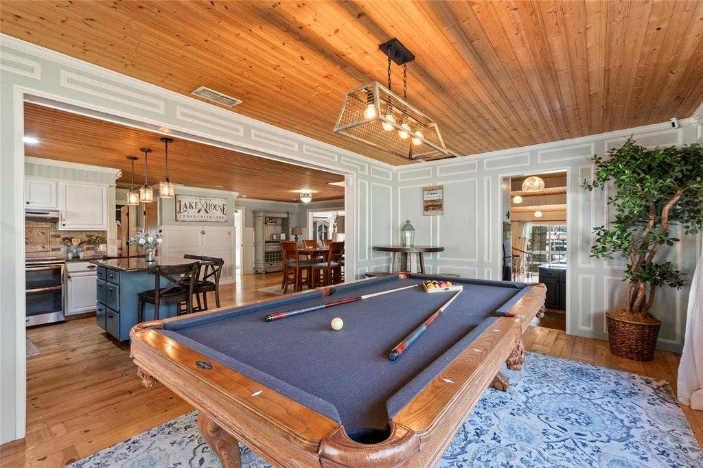 230 Bushwhacker Drive, Mabank, TX 75156 Tongue-and-groove wood plank ceiling, paneled wall detailing, natural wood-finish flooring, and a rectangular multi-light pendant fixture with a metal cage frame