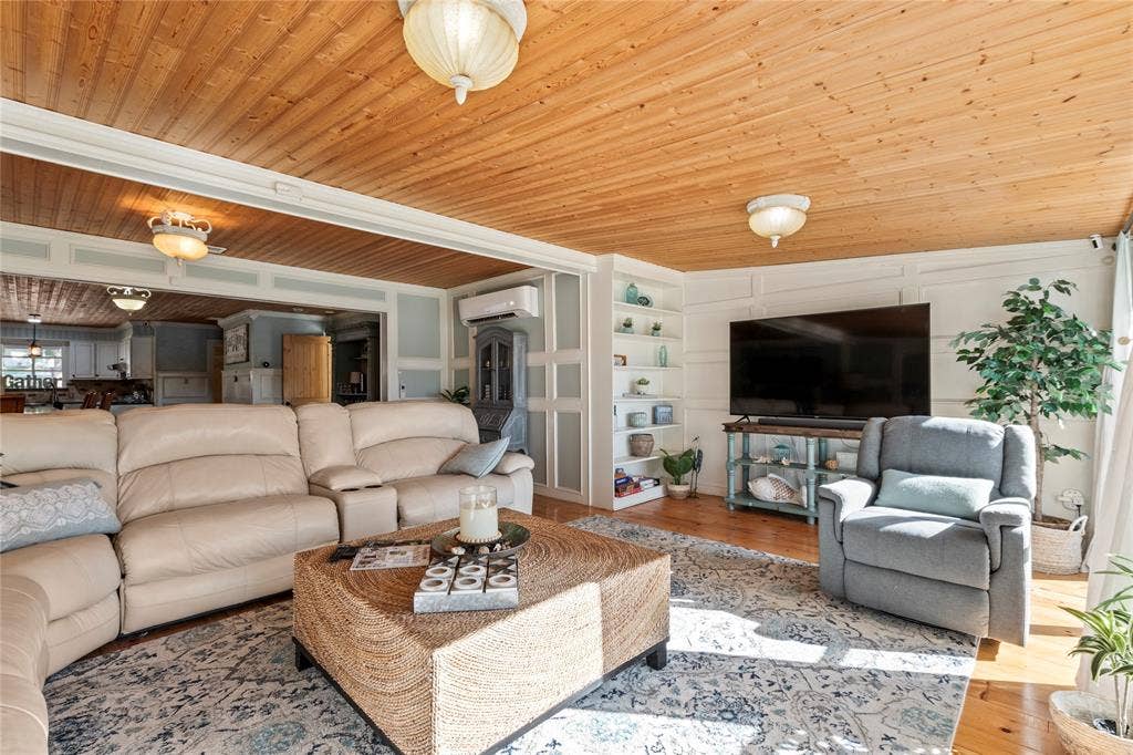 230 Bushwhacker Drive, Mabank, TX 75156 Natural wood-plank ceiling, wall paneling, built-in shelving, wall-mounted air conditioning unit, and wood-finish flooring