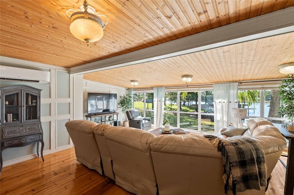 230 Bushwhacker Drive, Mabank, TX 75156 Vaulted natural wood-plank ceiling featuring decorative pendant lighting, wall-mounted ductless climate control system, paneled wainscoting, and expansive floor-to-ceiling windows