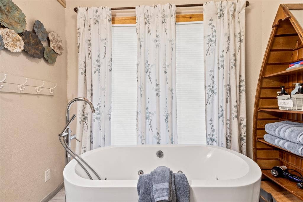 230 Bushwhacker Drive, Mabank, TX 75156 Freestanding jetted soaking tub featuring a chrome floor-mounted faucet and built-in wall-mounted coat rack