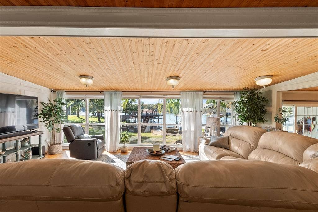 230 Bushwhacker Drive, Mabank, TX 75156 Natural wood-plank ceiling featuring flush-mount light fixtures, expansive floor-to-ceiling windows, and white vertical wainscoting