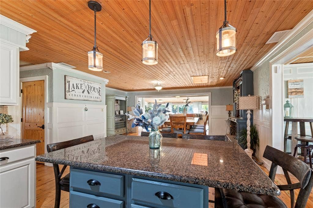 230 Bushwhacker Drive, Mabank, TX 75156 Kitchen featuring a central island with stone countertop, wood-plank ceiling, three industrial-style pendant lights, and beadboard wall paneling